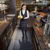Bar server behind a bar carrying a tray with two glasses of orange standing on a Morland Service Anti bacterial rubber industrial doormat