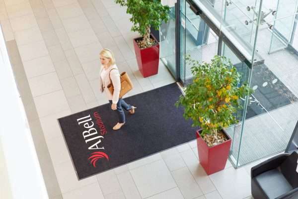 lady walking across a Large doormat in stadium entrance